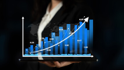 A businesswoman holds a tablet displaying a growth chart with increasing financial data. The image represents success, financial analytics, and professional growth in business settings. Tessel