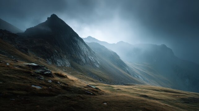 A mountain range with a cloudy sky in the background. The sky is dark and the mountains are covered in snow