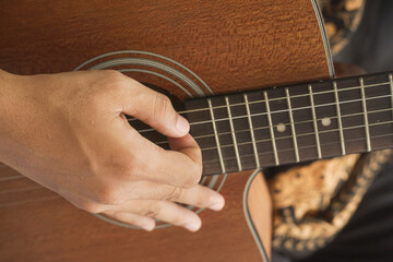 Close up of hands strumming and playing the acoustic guitar