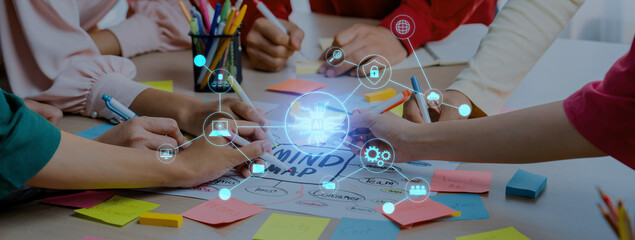 A dynamic workspace captures hands engaged in creating a mind map filled with sticky notes and digital icons, illustrating teamwork, creativity, and innovation in action. Trope