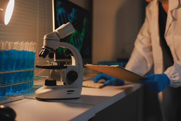 Scientist conducting research with microscope and test tubes in laboratory