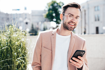 Handsome smiling stylish lambersexual model. Sexy modern man dressed in elegant beige suit. Fashion...