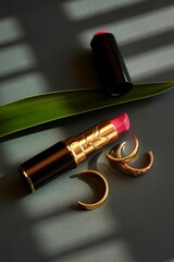 Luxurious lipstick and gold rings with aloe vera leaf and shadow play