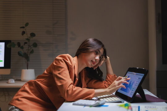 Tired businesswoman working late analyzing financial data at office desk