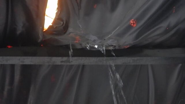 Close-up shot of a black ceiling heavily leaking due to severe weather, with continuous water dripping from a visible stain. The footage includes the dramatic sound of heavy rain and water damage.