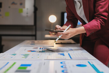 Businesswoman analyzing financial data and charts using smartphone