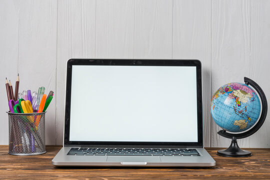 Laptop on wooden desk with white wall background ideal for online learning concept