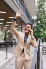 Fototapeta premium Asian businessman talking on phone and waving hand