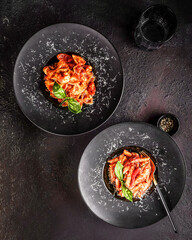 Comforting tomato pasta plated against textured dark surface ambiance