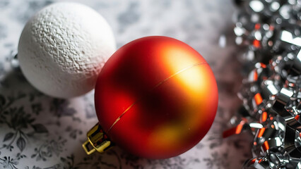 A close up of red and white christmas ornaments with silver tinsel on a floral background