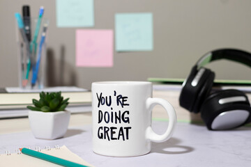 Workspace background motivational quote on mug with stationery and headphones