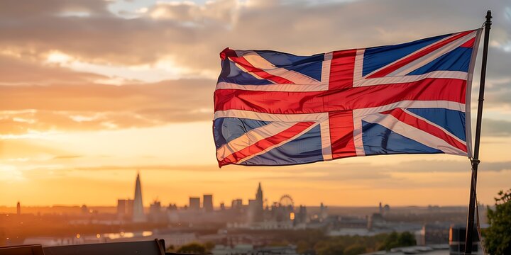 Iconic union jack flag waving proudly against a vibrant sunset sky with the london skyline in the background