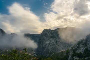 Cloud-wreathed mountain peaks emerging through dramatic morning mist