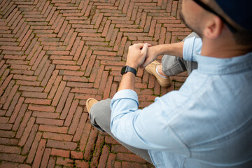 Man sits casually on a herringbone brick walkway