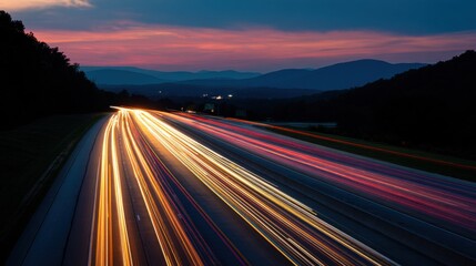 Obraz premium A highway with a long line of cars is illuminated by the bright lights of the cars, creating a beautiful and serene scene. The sunset in the background adds a sense of calmness