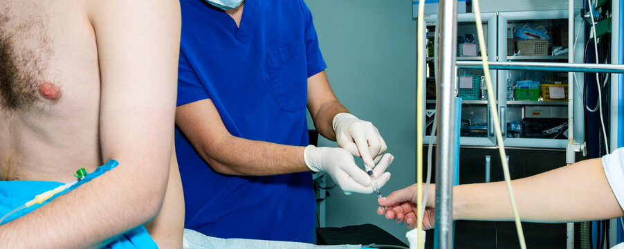 The doctor draws the medicine into a syringe to inject the patient. The anesthesiologist conducts and charges the syringe with anesthetics.