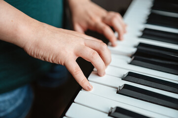 Obraz premium Close-up view of hands playing an electronic keyboard indoors.