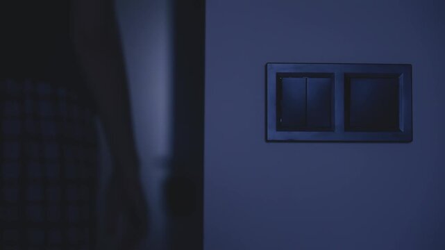 silhouette of person close-up shot hand turns off light in dark home room by pressing a switch. turning on the light saving electricity. woman go to sleep night darkness, expensive utility bills 4k.