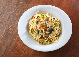 白い器に盛ったボンゴレビアンコ　木目背景