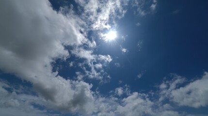 Obraz premium The sky is blue with a few clouds. The sun is shining brightly through the clouds. The sky is clear and bright