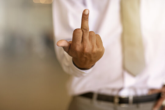 Hands, business man and middle finger in office for corporate anger, frustrated and work injustice. Space, rude employee and offensive gesture at workplace for rebellion, company conflict and opinion