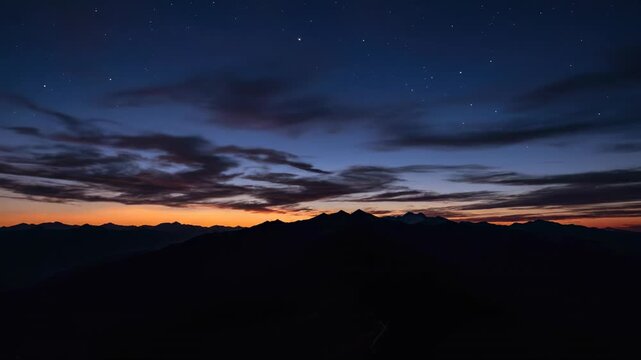 Cinematic aerial view of vivid post-sunset residual colors spread across high wispy clouds above a dark mountain range landscape fading into night purple, serene, dark mountain range landscape