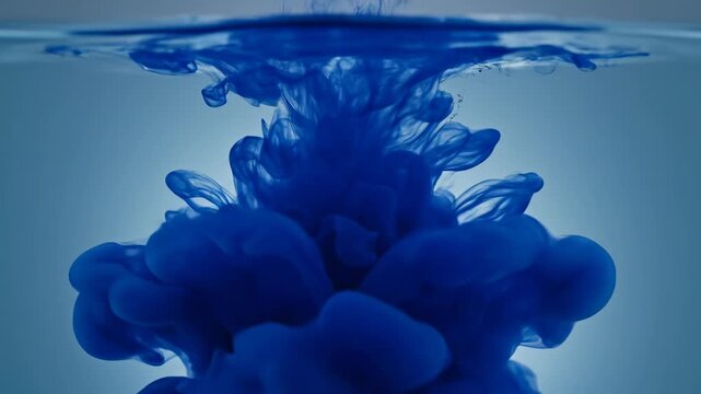 Extreme slow motion close-up of a single drop of vibrant sapphire ink hitting a perfectly still, clear water surface and expanding sapphire, high, ink
