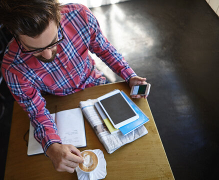 Man, phone and cappuccino at cafe for remote work, above and stir beverage with mockup space on screen. Person, freelance writer and cup for drink, smartphone and notebook for project at coffee shop - Powered by Adobe