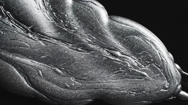 Extremely slow motion close-up of thick, shimmering metallic liquid ink flowing and separating into unpredictable, non-linear channels against a solid dark background thick, flowing, motion