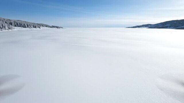 Extremely smooth aerial drone glide over a vast pristine field of unbroken fresh snow emphasizing uniform texture and expansive natural blankness untouched, winter, quiet