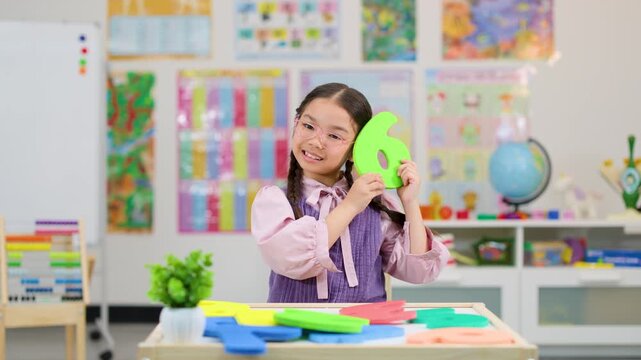 Young Student Smiling With Foam Number Six in Classroom
