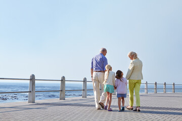 Grandparents, ocean and walking with girls, back and bonding together with vacation. Promenade,...