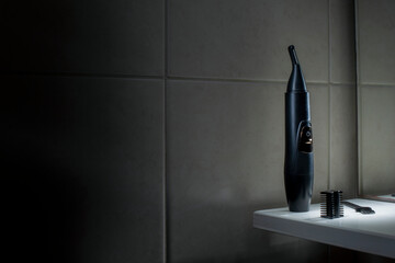 Nose trimmer against the background of ceramic tiles in the bathroom.