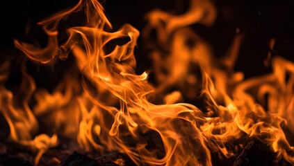 Fototapeta premium Intense close up of vibrant orange and yellow flames dancing in darkness with a fiery glow