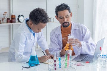 Cheerful African boy and Indian teacher with mustache wearing lab coat uniform studying science class in laboratory, pupil boy show test result to scientist professor with microscope and test tube
