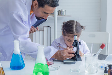Hispanic or Indian teacher wearing lab coat concentrate on elementary students girl kid using microscope in laboratory science class, lifestyle modern education at school for elementary pupil concept