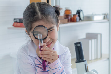Cute Arabian girl elementary student kid wearing lab coat standing near microscope hold glass magnifier looking at camera in laboratory classroom, lifestyle learning education science class scientist