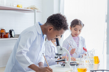 Close-up group of multicultural cute elementary students kids wearing lab coat uniforms using...