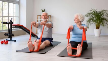 Senior couple exercising together on yoga mats in a bright home gym, using resistance bands for stretching. - Powered by Adobe