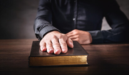 Oath. Hand on the Holy Bible. Taking the oath of allegiance. Sitting at the table a man in a shirt and jacket