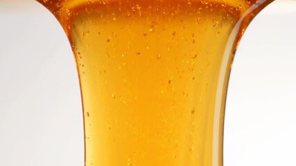 Extreme close up slow motion shot of thick, warm honey-colored liquid slowly flowing and cascading down a completely blank vertical surface detail, health, amber