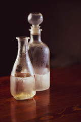 A chilled drink in frosted glass bottles of gin or vodka, decanters on a wooden table, creating a cozy winter pub atmosphere with warm holiday lighting.