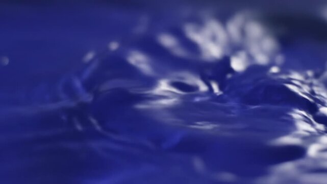 Extreme slow motion close-up of gentle ripples moving across an indigo blue water surface texture, ocean, slow