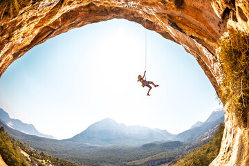A climber hangs on a rope. A female climber descends. Rock climbing in Turkey. A woman engaged in...