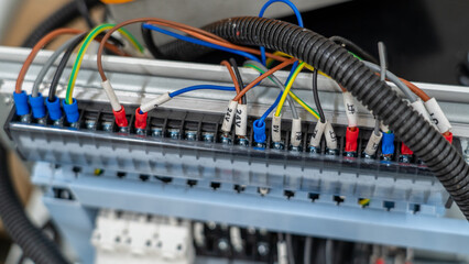 Close up of electrical terminal block with colorful labeled wires in industrial control panel