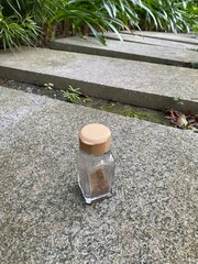 Glass Spice Jar with Brown Seasoning on Outdoor Stone Background
