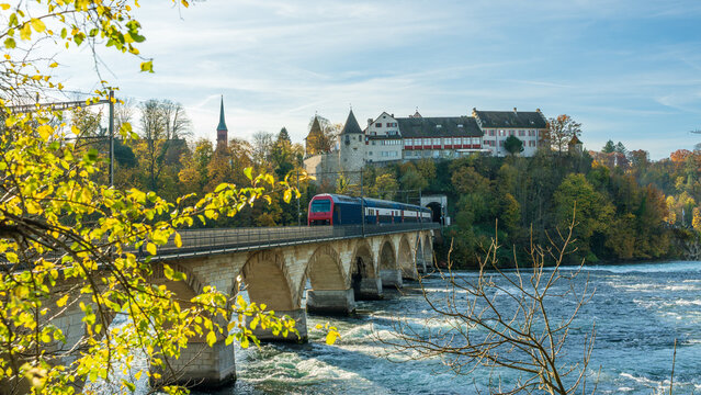 Rhine Falls Autumn landscape. Train crossing Rheinbruecke bei Laufen bridge. Schaffhausen, Switzerland.