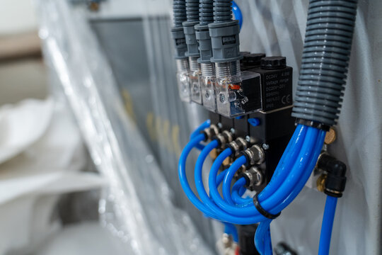 Industrial pneumatic and electrical connections with blue hoses on control manifold