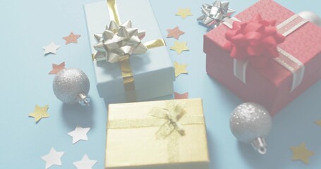 Fototapeta premium Showing three wrapped gift boxes sitting on pale blue table, with metallic bows and silver baubles