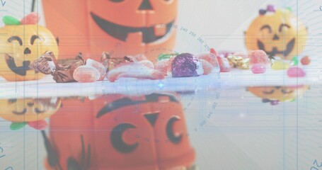 Fototapeta premium Displaying assorted Halloween candies and jack-o'-lantern buckets on glossy tabletop, blue overlay
